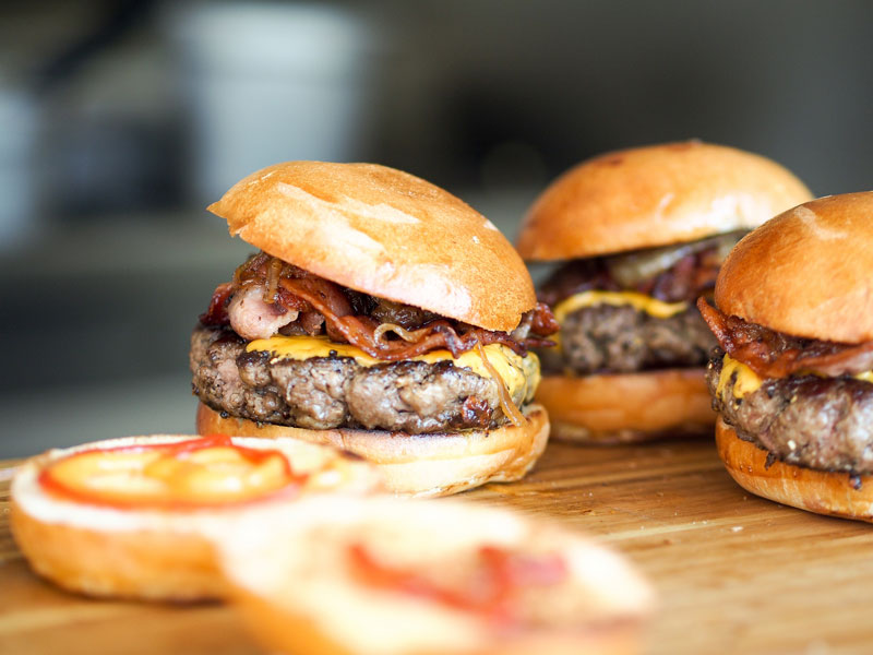close-up of two open buns and three cheeseburgers