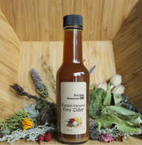 a bottle of fire cider on a basket of dried botanicals