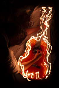 a woman holding a flaming guitar
